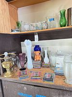 shelves with glass vases, bowls, brass lamp, CDs, bear figurine, Crock-Pot