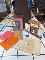 All items together on countertop: miniature house, gate, open recipe journal, four booklets