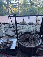 Fire pit with hoist frame, round grate, extra grates and hooks visible