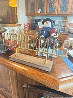 Tabletop sign displaying CHRISTMAS in gold-tone metal letters on wood base