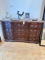 Front view of dark brown dresser showing nine drawers and faux marble top