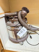 Filter Queen canister vacuum with hose and attachments on shelf