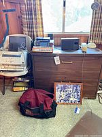 Front view showing cabinet, subwoofer, books, phone, lamp, duffel, framed print