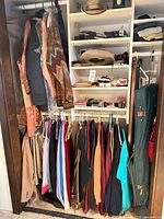 Closet view with hanging shirts, sport coats, belts, hats, accessories