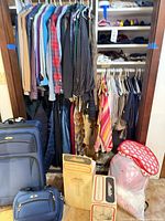 Closet with hanging clothing, Aladdin lamp boxes, bedding bag, luggage visible