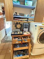 Full view of cabinet, drawers open, clock, HP tower, washer adjacent