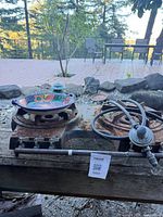 Top view of two-burner stove showing ceramic pan and regulator hose