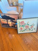 Both framed prints leaning against floor