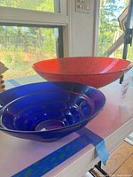 Red and blue glass bowls side by side on table
