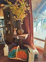 Overall lot showing table, vase with stems, angel figurine, basket with placemats, candles