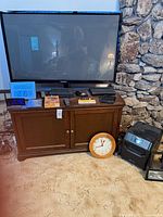 Overall view showing Samsung TV, wood console, clocks, remote controls, DVDs, space heater