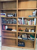 full view of double-wide oak bookcase with shelves and assorted contents
