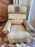 Front view of tan leather swivel recliner chair showing wear on seat and arms