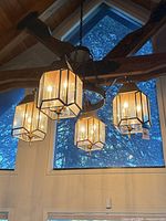 Chandelier lit, showing five glass lantern shades, brass frames, iron ring and chain mounting