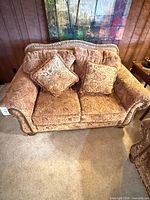Front view of loveseat showing upholstery, nailhead trim and two throw pillows