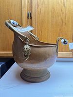 Left side view showing copper body, pedestal base, swing handle with porcelain grip, lion head mount