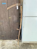 Full view of scythe leaning against cabinets and fridge