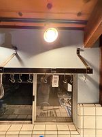 Front view of wall-mounted pot rack with support brackets and hanging S-hooks