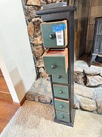 Full view of tall narrow CD storage tower with six green-front drawers