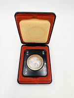 Coin in open presentation case showing red flock interior and black holder