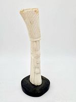 Full view of carved bone figure on base, front profile