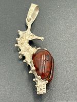 Front view of sterling silver seahorse pendant showing amber cabochon