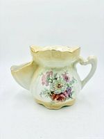 Front view of porcelain shaving scuttle mug with floral design and gilt accents
