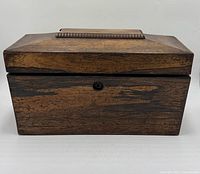 Front view of closed wooden tea caddy showing lock escutcheon and grain