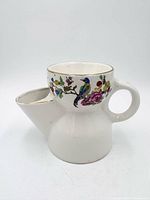 Side view of porcelain shaving scuttle showing spout, handle, bird and floral decoration