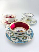 Three distinct bone china cup and saucer sets grouped together