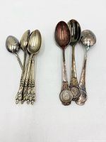Group of six ornate demitasse spoons and three souvenir spoons displayed on white background