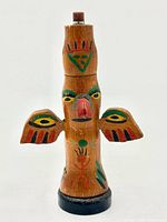 Front view of carved wooden totem pole with painted details and wings