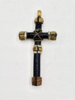 Front view of cross pendant showing dark obverse, twisted wire center, metal collars and loop