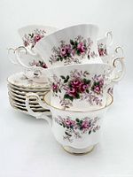 Stacked tea cups and saucers showing floral pattern and gold trim