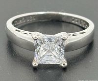 Top view of sterling silver ring showing princess-cut stone and band inscription