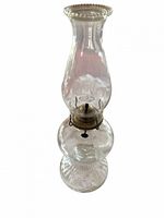 Full view of clear glass hurricane oil lamp showing chimney, burner, font and base