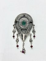 Front view showing full design, filigree detail, green cabochon and red bead drops