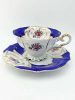 Teacup on saucer showing cobalt blue border, gold gilding, floral interior