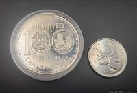 1974 Winnipeg specimen silver dollar in capsule beside 2007 quarter