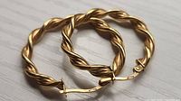 Both twisted gold hoop earrings close-up