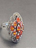 Side view of sterling silver ring showing orange stones and marcasite border