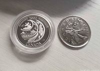 Two coins side by side, silver Ingenuity quarter in capsule and standard caribou quarter