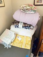 Stack of pillow, blankets and comforters showing majority of items