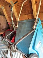Blue metal garden cart and red spreader frames inside shed
