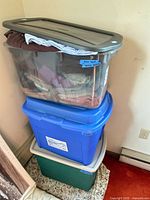 Stack of three plastic bins containing folded clothing