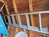 Side view of aluminum extension ladder hung on shed wall