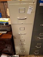 Full view of beige five-drawer metal file cabinet with handles and label plates