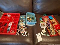 overview of jewelry pieces in red and blue organizers on couch
