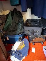 Blue and grey rolling suitcases with green duffle and blue drawstring bag