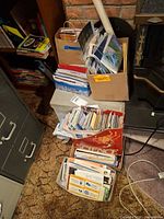 Multiple boxes and bags filled with assorted maps and brochures next to filing cabinet
